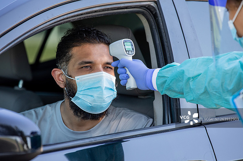 护士在男性患者的车内使用额温枪图片素材