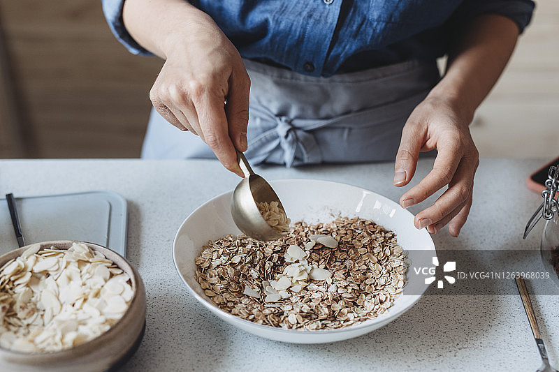 一位匿名妇女将杏仁放入盛有燕麦片的碗中图片素材