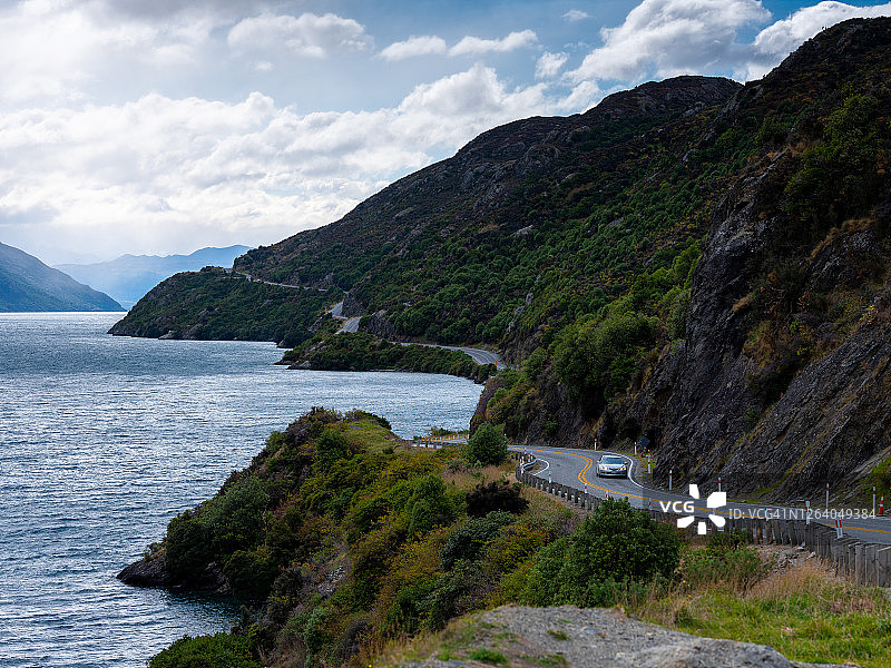 新西兰弯曲山丘和湖边道路上的一辆汽车图片素材