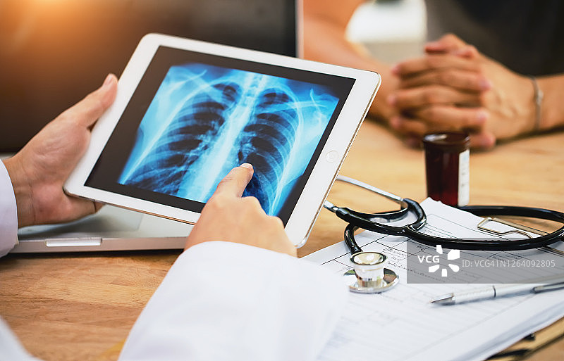 肺癌概念：医生向患者讲解数字平板电脑上X光胸透检查结果图片素材