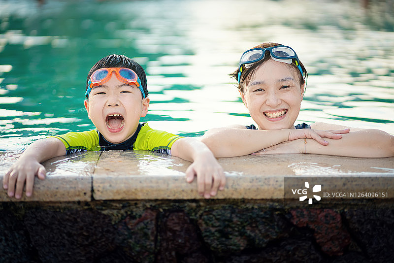 阳光明媚的日子里，母子在泳池里度假玩耍图片素材