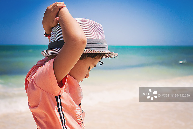 在加勒比海滩向下看的小卷发男孩图片素材