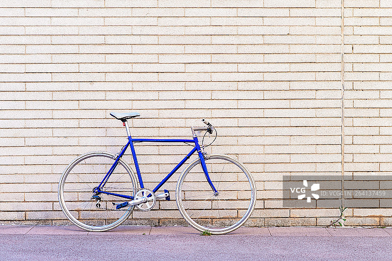 靠在城市砖墙上的蓝色复古自行车图片素材