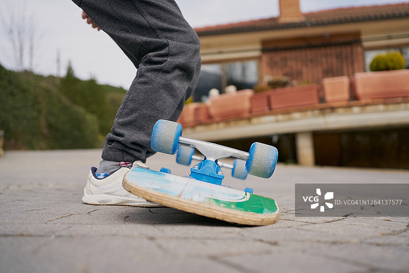 穿着运动鞋的孩子在沥青路上骑着破旧的滑板的裁剪照片图片素材