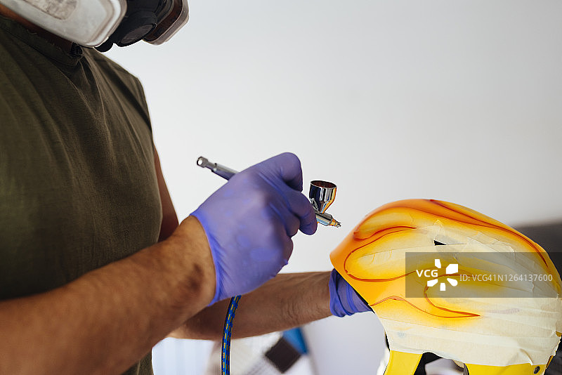 画家在头盔上绘制火焰的双手特写图片素材