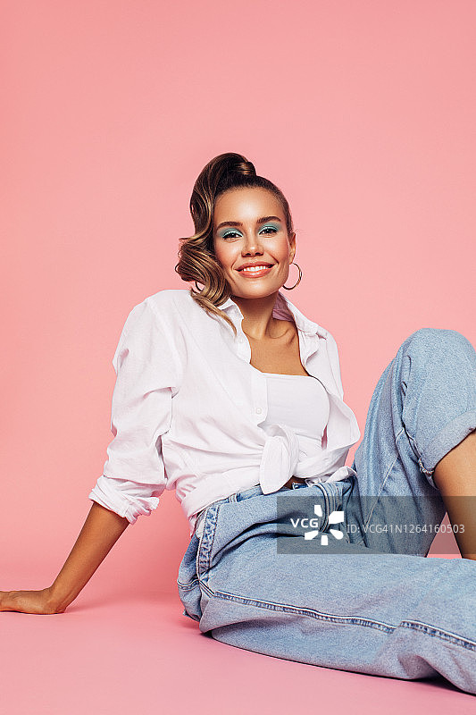 身穿80年代风格服装的女孩坐在工作室的地板上图片素材