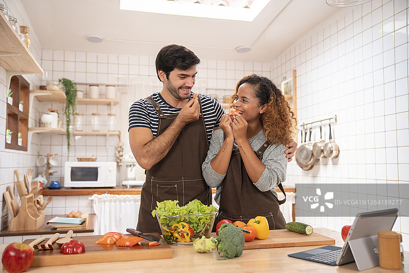 年轻夫妇在厨房灶台上烹饪鱼类美食图片素材