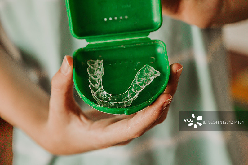 青少年男孩在家手持牙齿矫正器特写图片素材