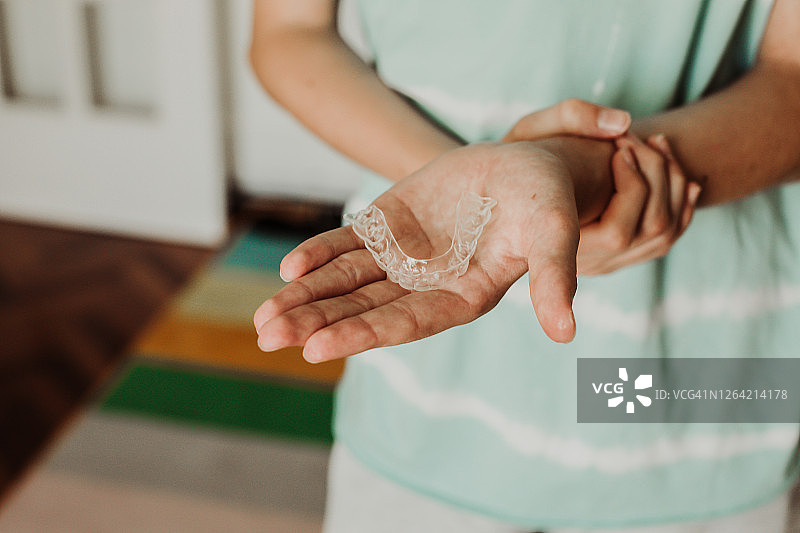 青少年男孩在家手持牙齿矫正器特写图片素材