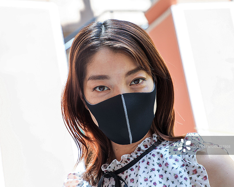 戴着黑色口罩看着镜头的日本女人图片素材