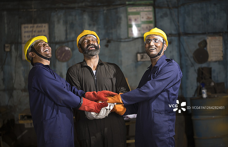 三名工人团结协作，手叠在一起图片素材