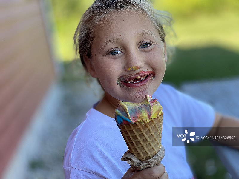 拿着融化的彩虹色冰淇淋的年轻女孩图片素材