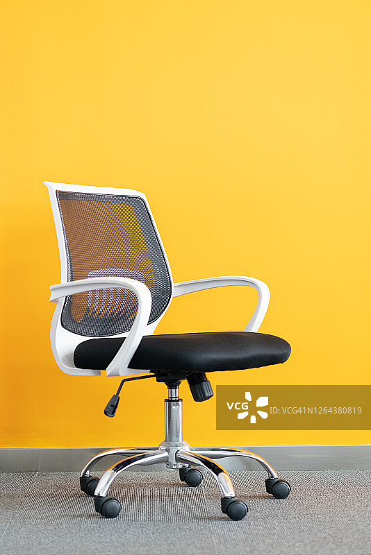 黄色背景前的办公椅图片素材