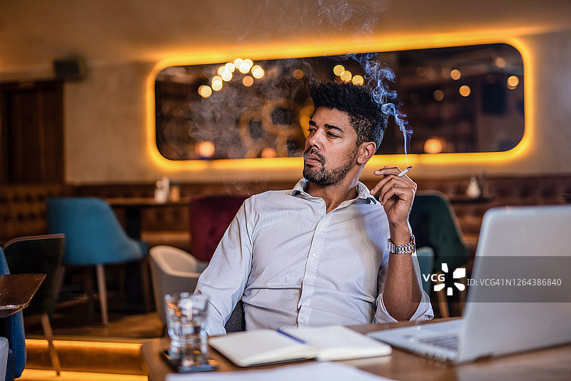 年轻男子在酒吧里抽烟图片素材