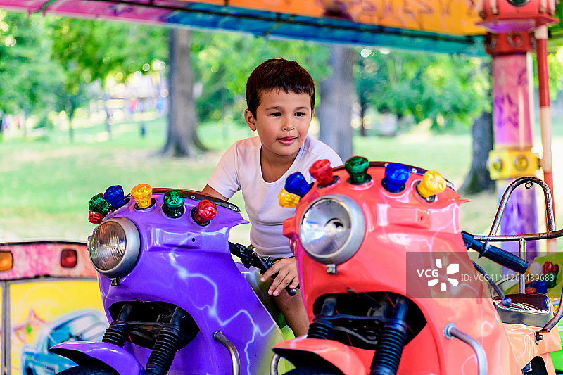 小男孩在游乐园的旋转木马上玩耍图片素材