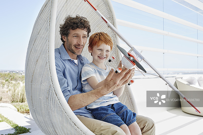 幸福的父子在悬挂椅上玩模型飞机图片素材