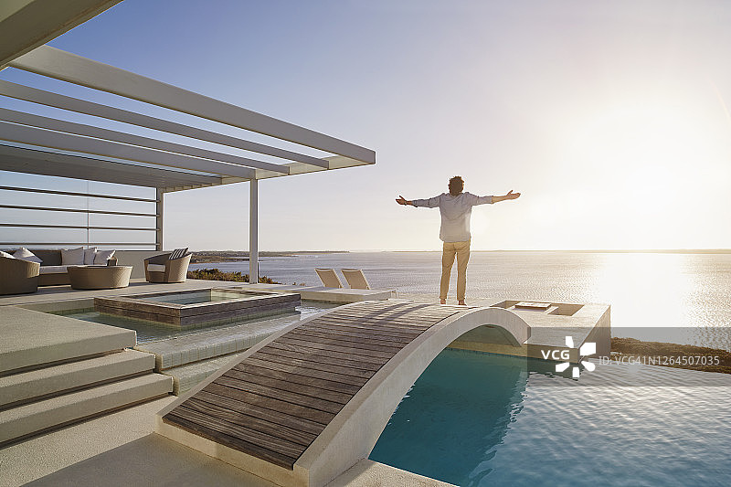 男人站在游泳池上方的桥上欣赏风景图片素材