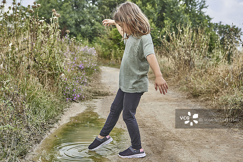 站在土路上玩水坑的女孩图片素材