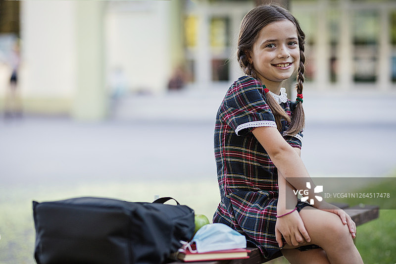 在户外长椅上休息的可爱女学生图片素材