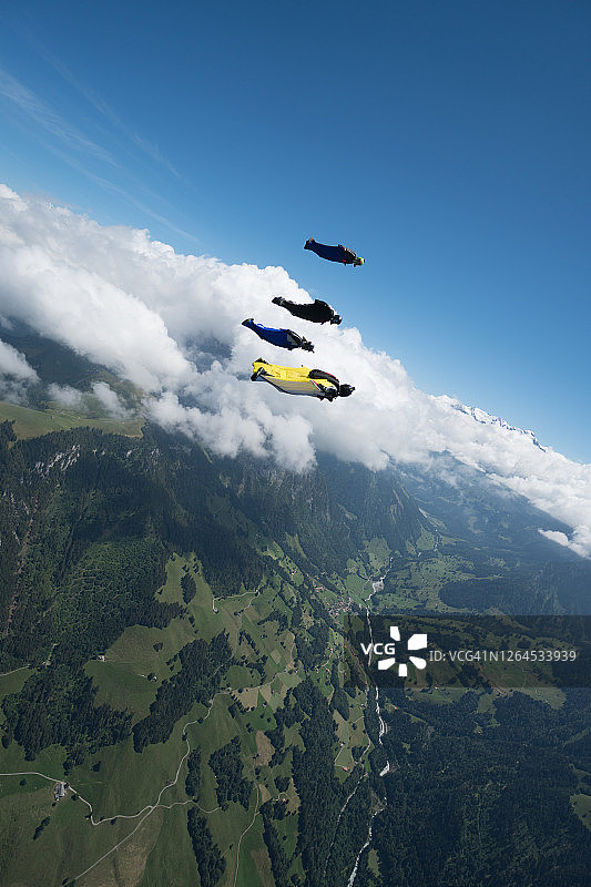 一群翼装飞行员在山脉和云层之上编队飞行图片素材