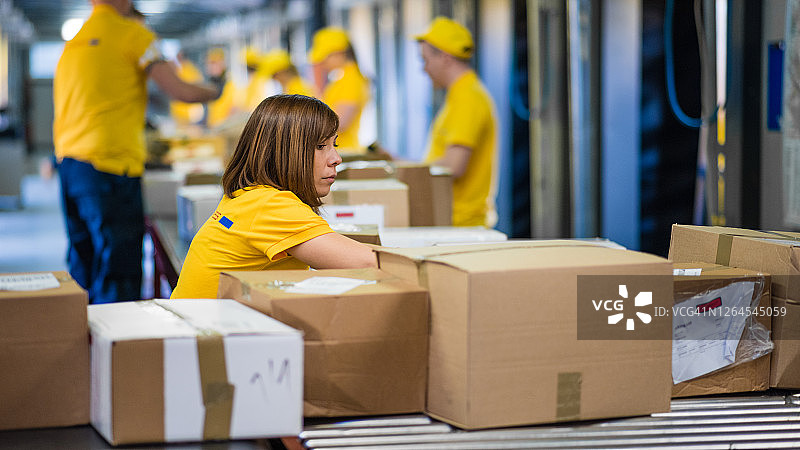 邮局工作人员在传送带上分拣箱子图片素材