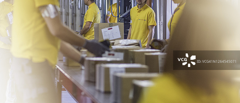 邮政工人在传送带上搬运箱子图片素材