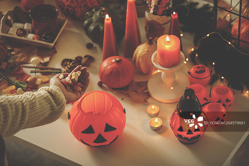 高角度拍摄的手将糖果放入南瓜篮图片素材