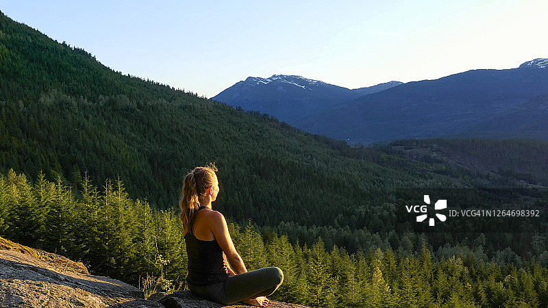 年轻女子在岩石上做瑜伽图片素材