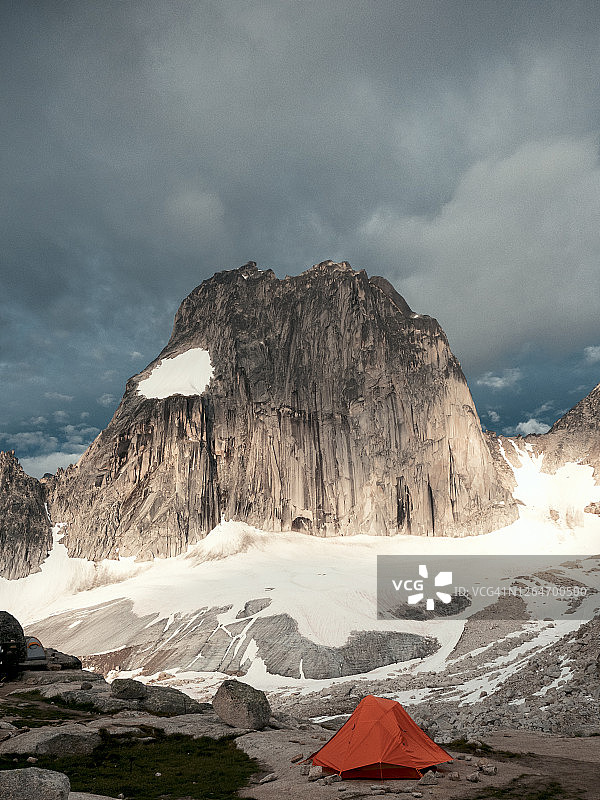 布加布冰川省立公园阴天日出时分雪斑峰下的橙色帐篷图片素材