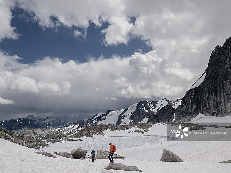 登山者在冰山湖泊旁的雪地中徒步图片素材