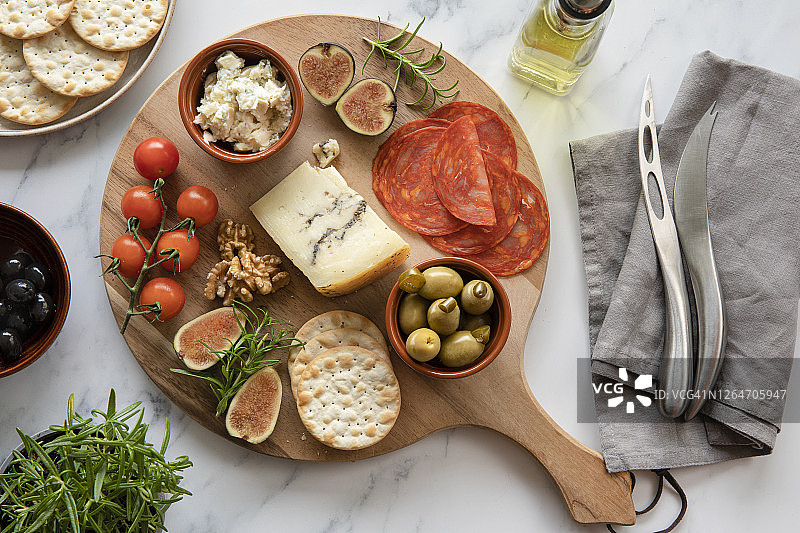 圆木板上的奶酪、西红柿、西班牙香肠、饼干、橄榄拼盘图片素材