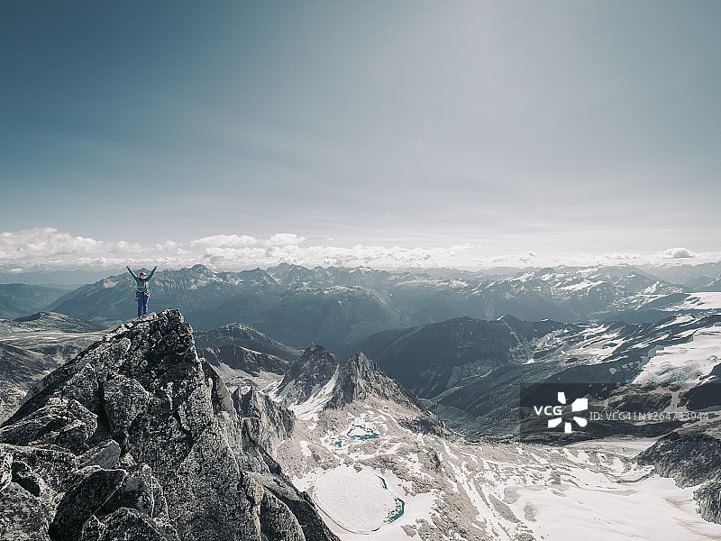 女攀岩者站在布加布尖顶上高举双手图片素材