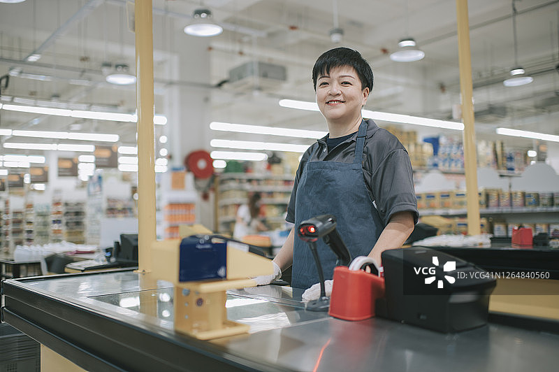在超市工作的亚洲中年女收银员图片素材
