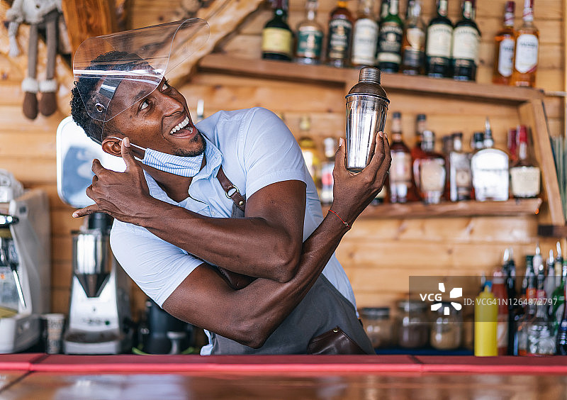 新冠疫情期间，调酒师戴着防护面罩为顾客准备鸡尾酒图片素材
