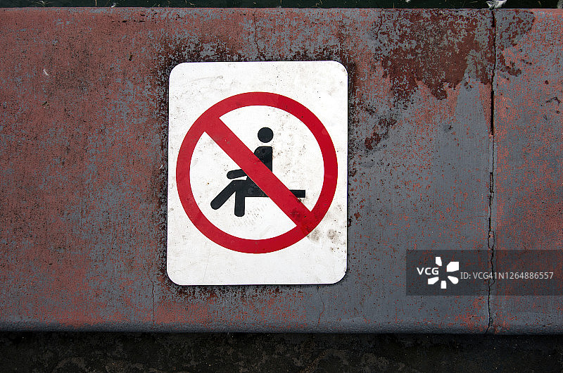 池塘边缘的“禁止坐下”警告标志图片素材