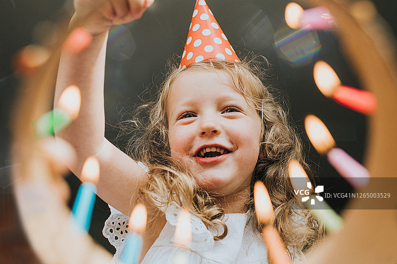 可爱的小女孩看着生日蛋糕，准备吹灭蜡烛图片素材