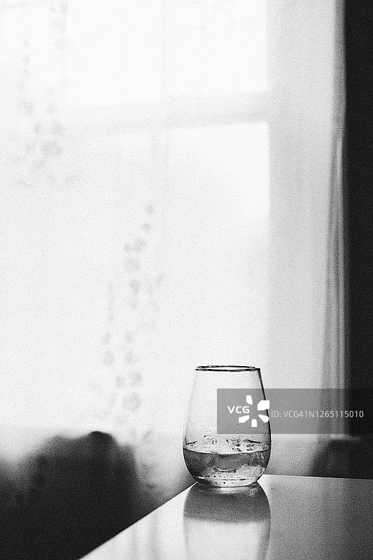 窗前柜台上未装满的玻璃杯倒影 II图片素材