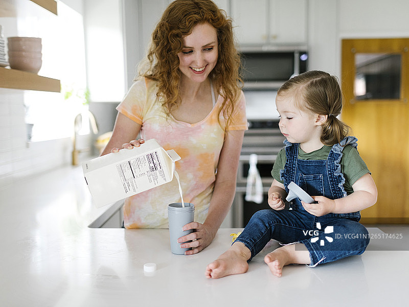 母亲为女儿倒牛奶（2-3岁）图片素材