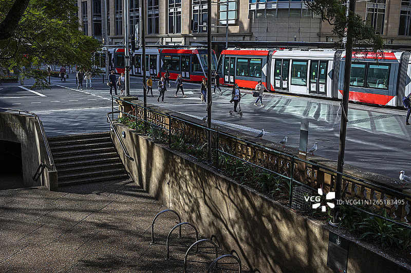 城市街道上的红色有轨电车和保持社交距离的行人图片素材