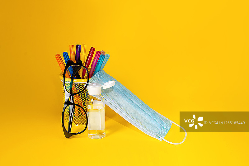 黄色背景上的学习用品和医用口罩图片素材