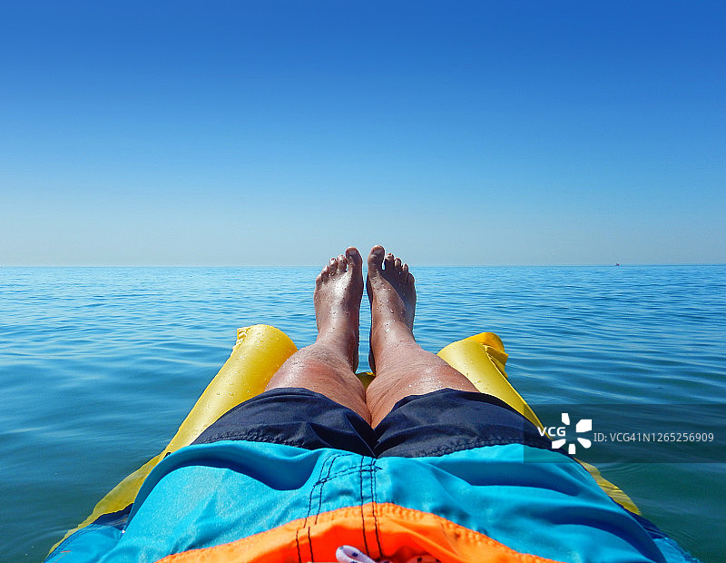 夏日海边男人在充气垫上休闲。图片素材