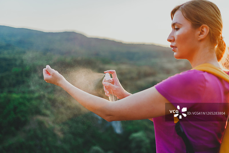 徒步旅行中，女人在户外使用驱蚊喷雾图片素材