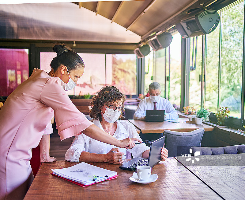 疫情期间，办公室里的同事戴着医用口罩工作图片素材