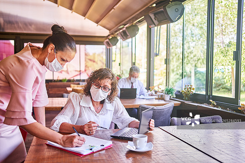 疫情期间，办公室里的同事戴着医用口罩工作图片素材