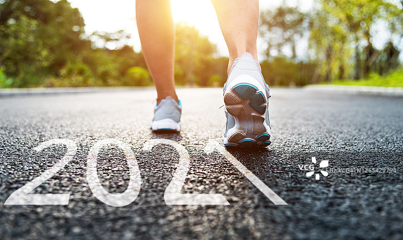 穿着跑鞋站在路上的女人，路面数字2021图片素材