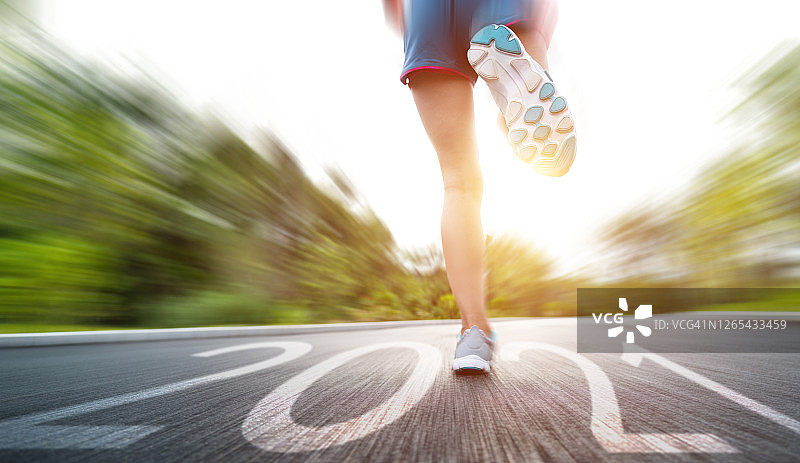 在带有2021数字的沥青路上跑步的女人腿图片素材