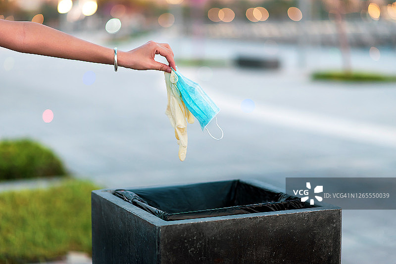 女人将用过的防护口罩和手套扔进垃圾桶图片素材