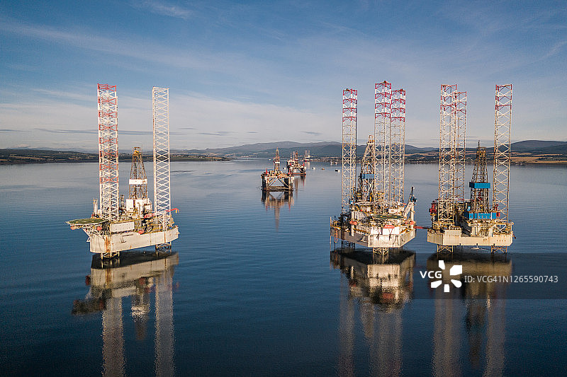 无人机低角度拍摄：苏格兰克罗默蒂湾石油钻井平台在平静海面的倒影图片素材