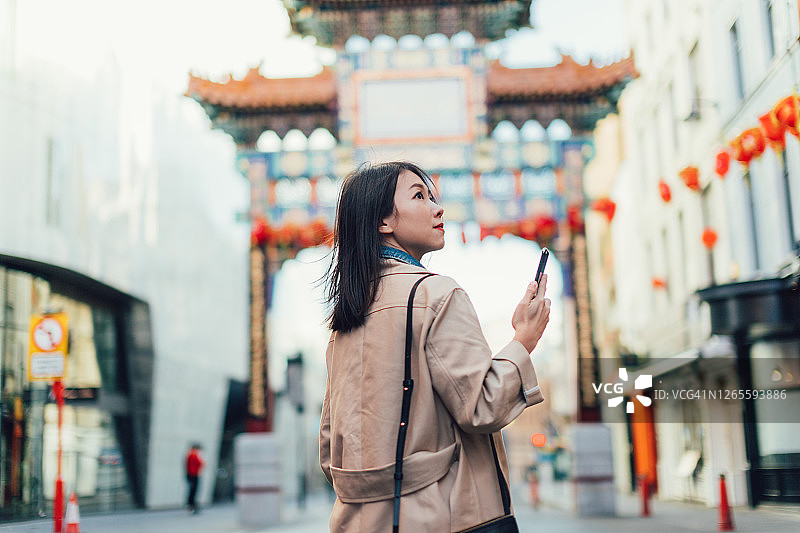 在伦敦唐人街用智能手机探索的年轻女人图片素材