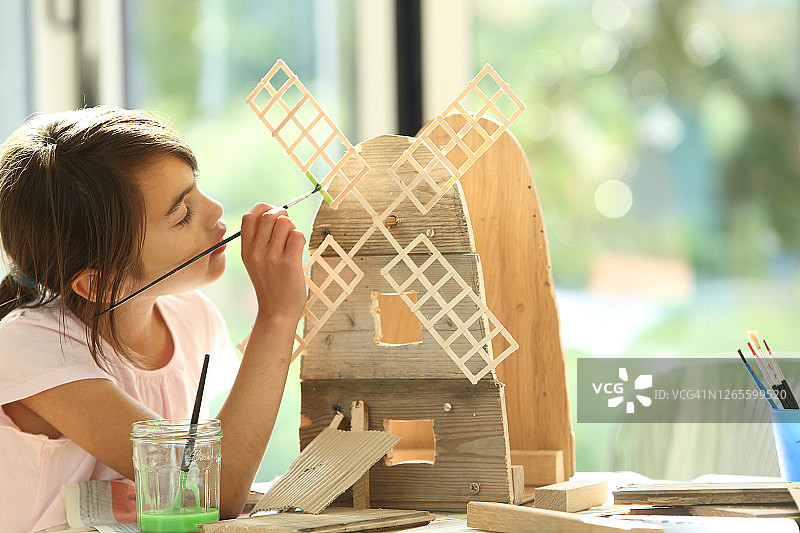 女孩给木制风车上色图片素材
